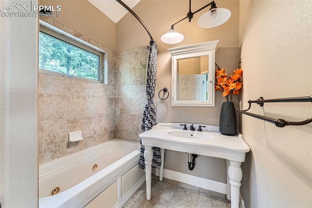 Bathroom with a combined bath / shower with jetted tub and tile patterned floors