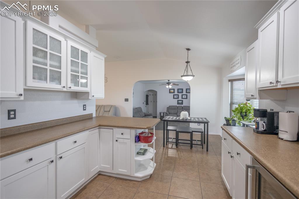 Kitchen featuring arched walkways, a peninsula, white cabinetry, a ceiling fan, and open shelves