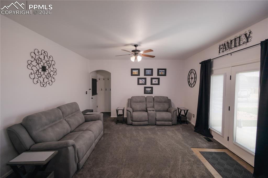 Carpeted living area featuring arched walkways and a ceiling fan