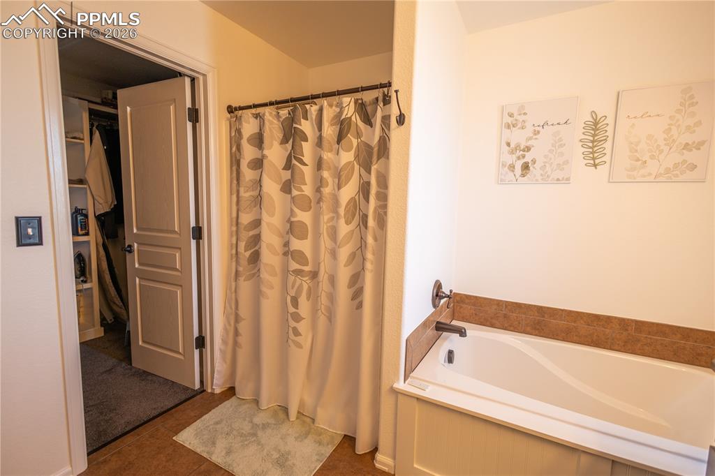 Bathroom with a shower with shower curtain and a garden tub