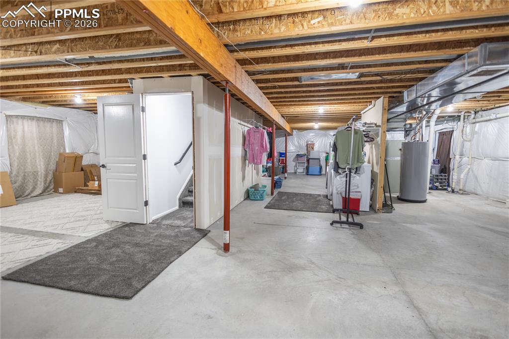 Unfinished below grade area with water heater, stairway, and drainage system