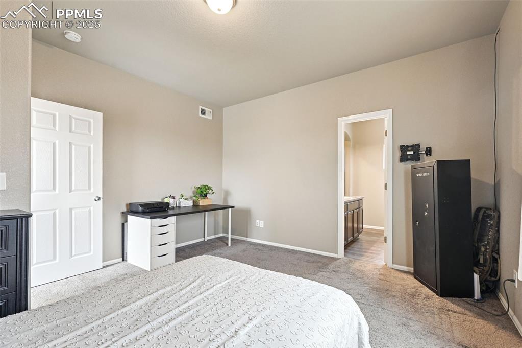 Bedroom featuring light colored carpet and ensuite bathroom
