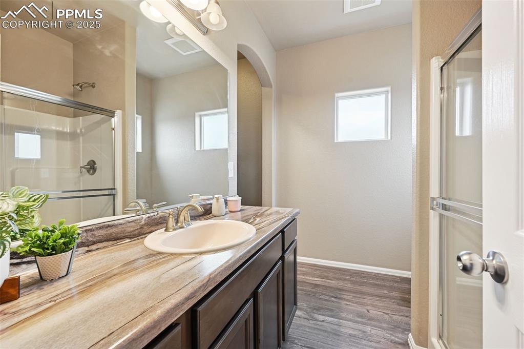 Bathroom with vanity, a shower stall, and dark wood-style flooring