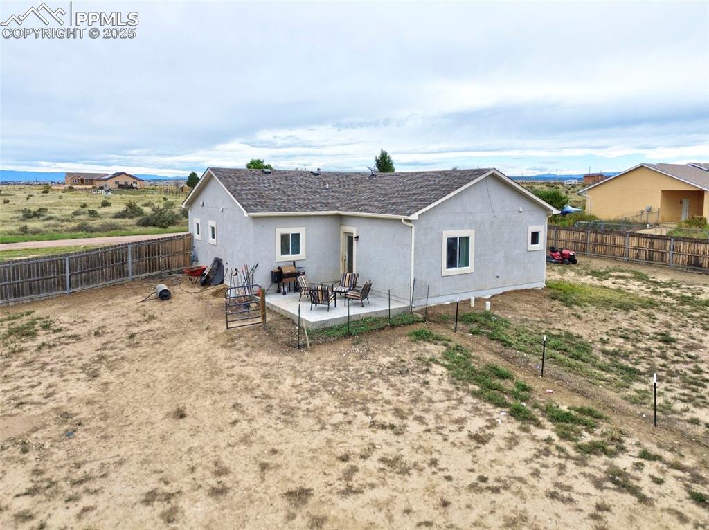 Rear view of house with a patio area, stucco siding, and a fenced backyard