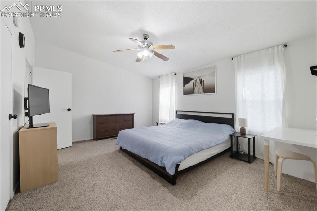 Bedroom with light colored carpet and a ceiling fan