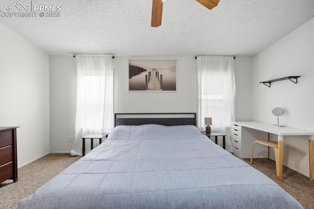Bedroom featuring light carpet, a ceiling fan, and a textured ceiling