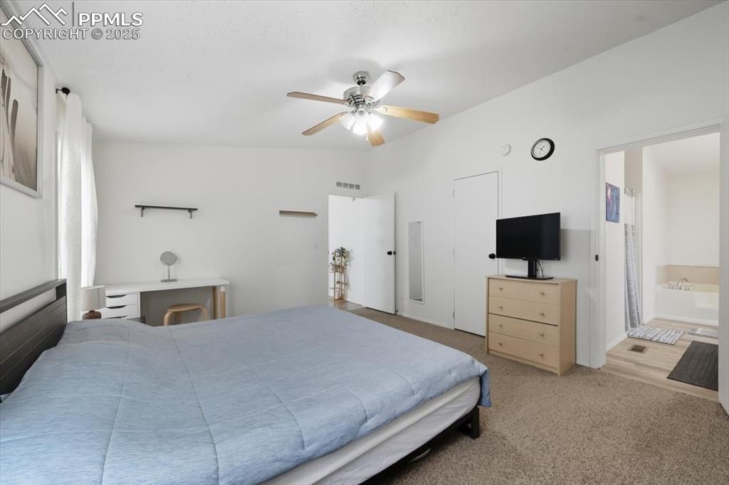 Bedroom featuring carpet floors, ceiling fan, and ensuite bathroom