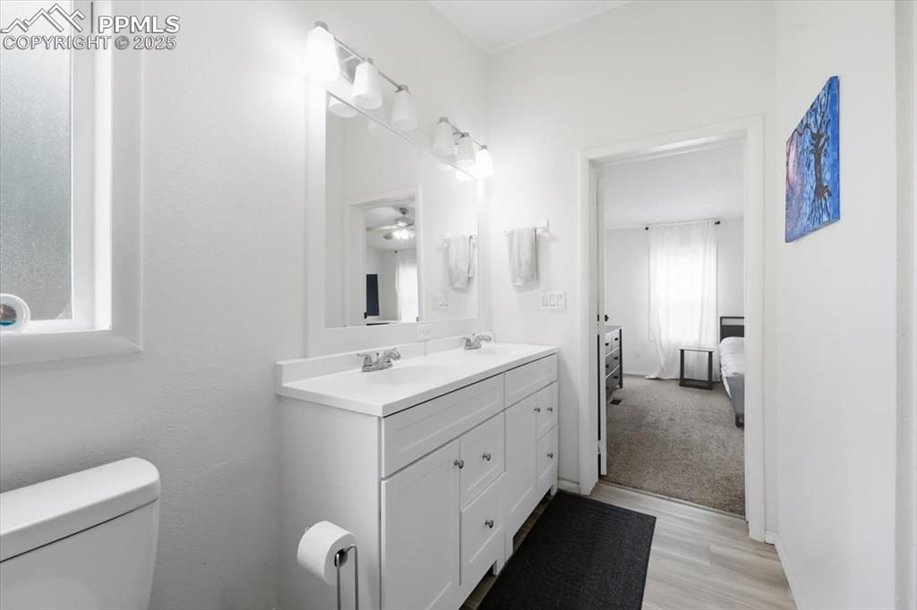 Ensuite bathroom with double vanity and light wood-style flooring