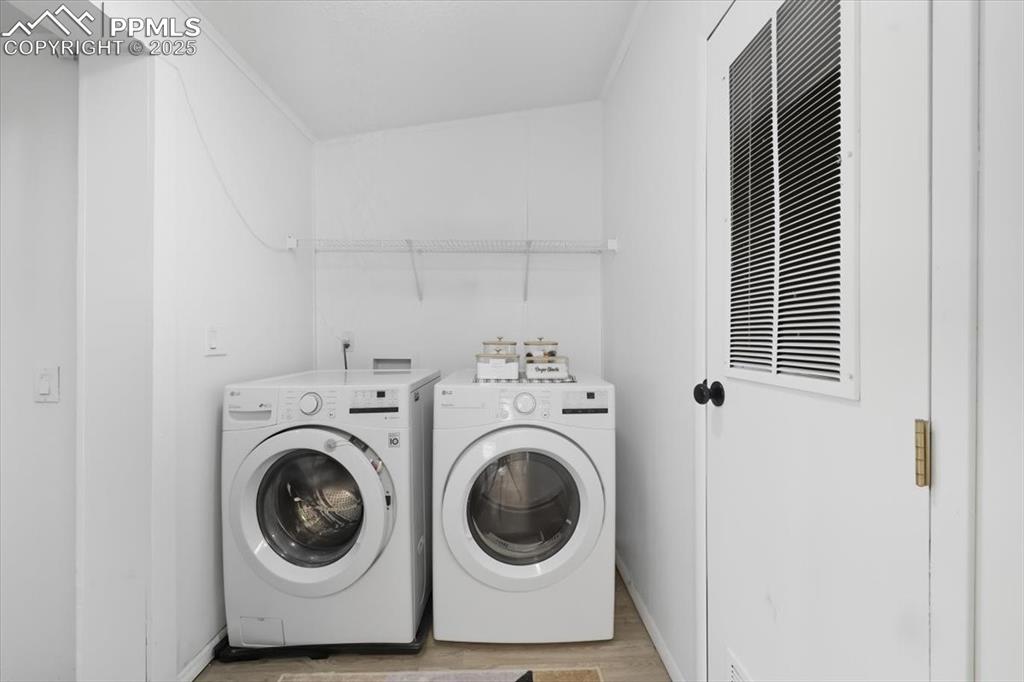 Laundry area with light wood-style flooring and washer and clothes dryer