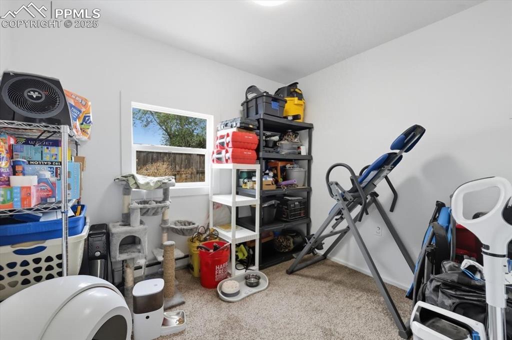 Workout area featuring light carpet and baseboards