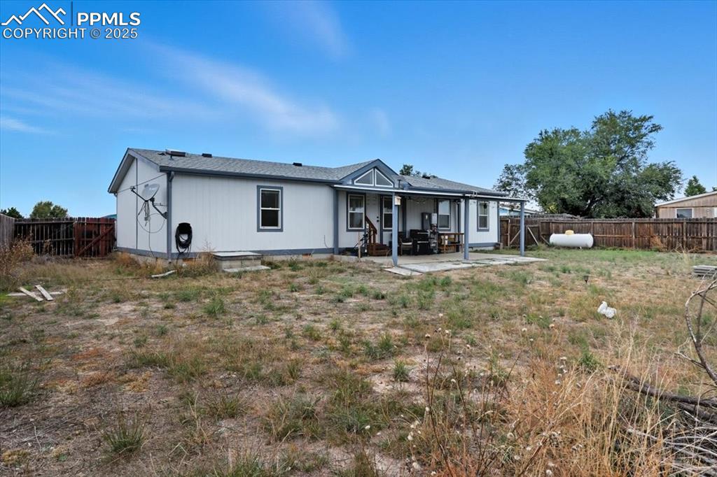 Rear view of house with a fenced backyard and a patio area