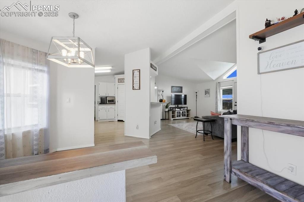 Dining space with light wood-style floors, a chandelier, and vaulted ceiling