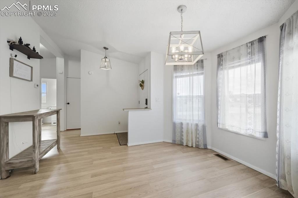 Unfurnished dining area featuring light wood finished floors and a chandelier