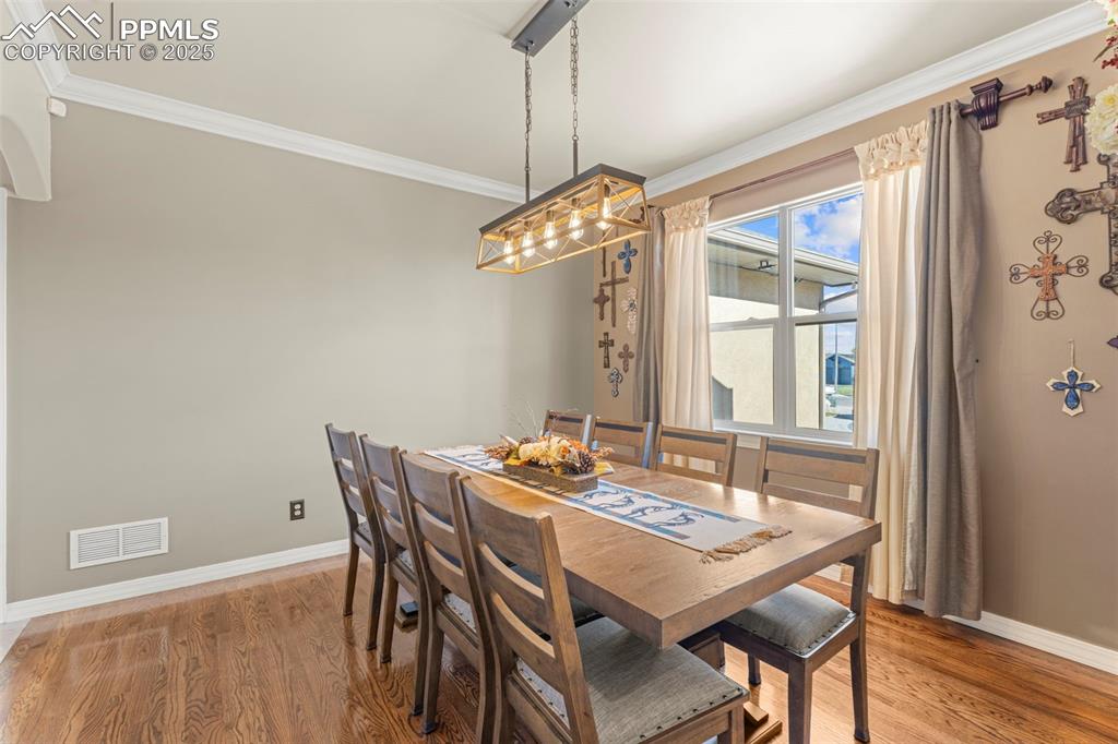 Dining space featuring crown molding and light wood finished floors