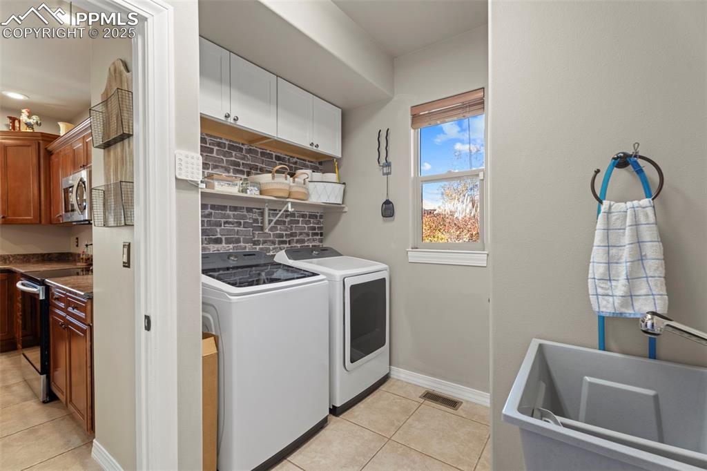Laundry room featuring light tile patterned flooring, washer and clothes dryer, and recessed lighting