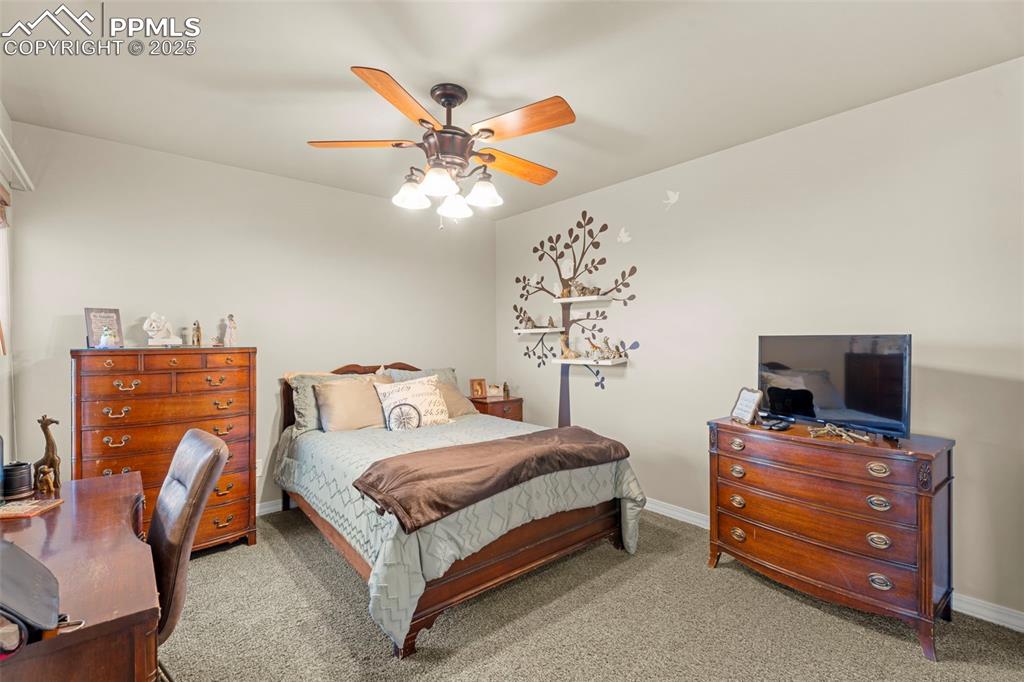 Carpeted bedroom with ceiling fan and a desk