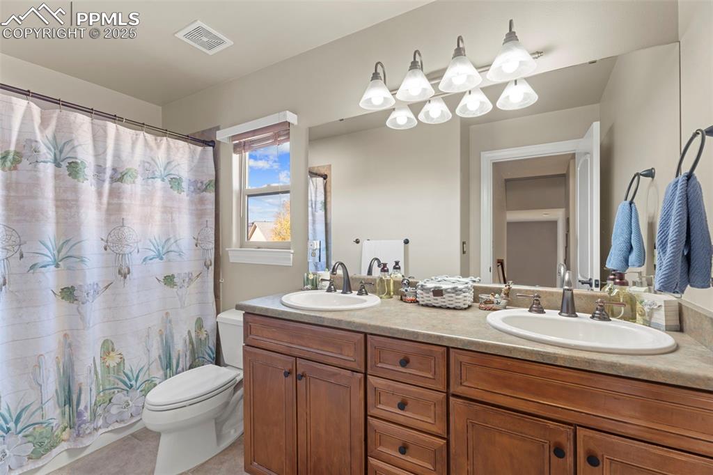 Full bath featuring double vanity, curtained shower, and light tile patterned floors
