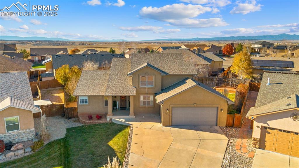 View of front of home featuring a residential view, stucco siding, concrete driveway, an attached garage, and roof with shingles
