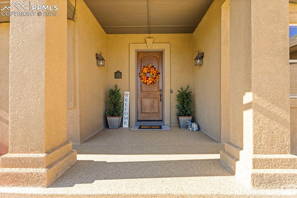 Doorway to property with stucco siding and covered porch