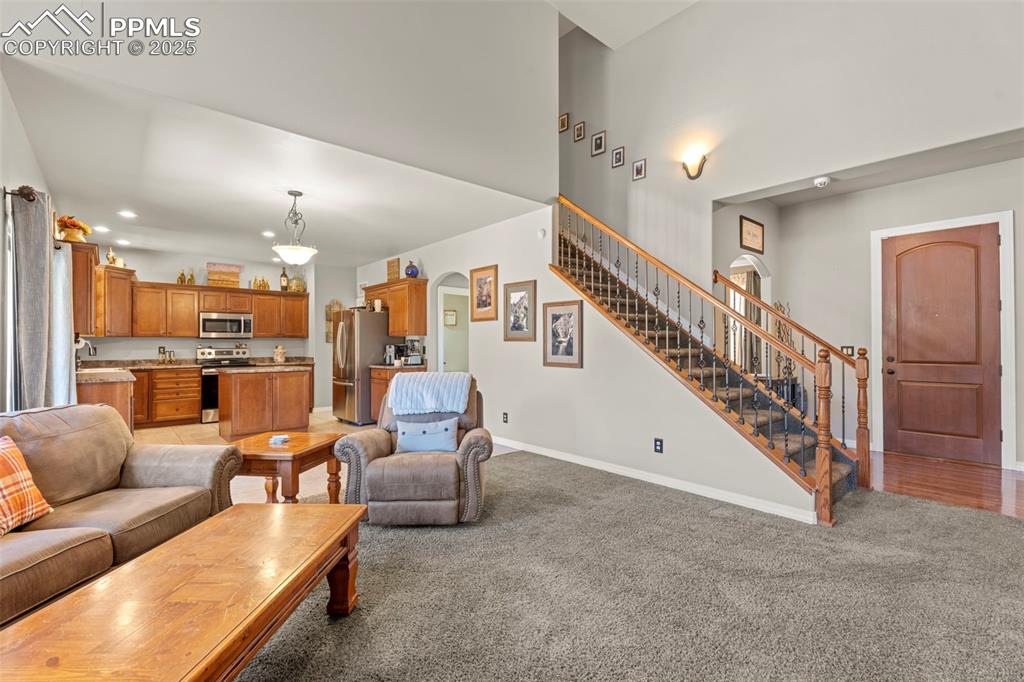 Living room featuring arched walkways, light colored carpet, recessed lighting, and stairs