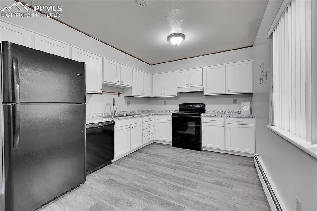 Kitchen featuring black appliances, a baseboard heating unit, white cabinets, light stone countertops, and light wood-style flooring