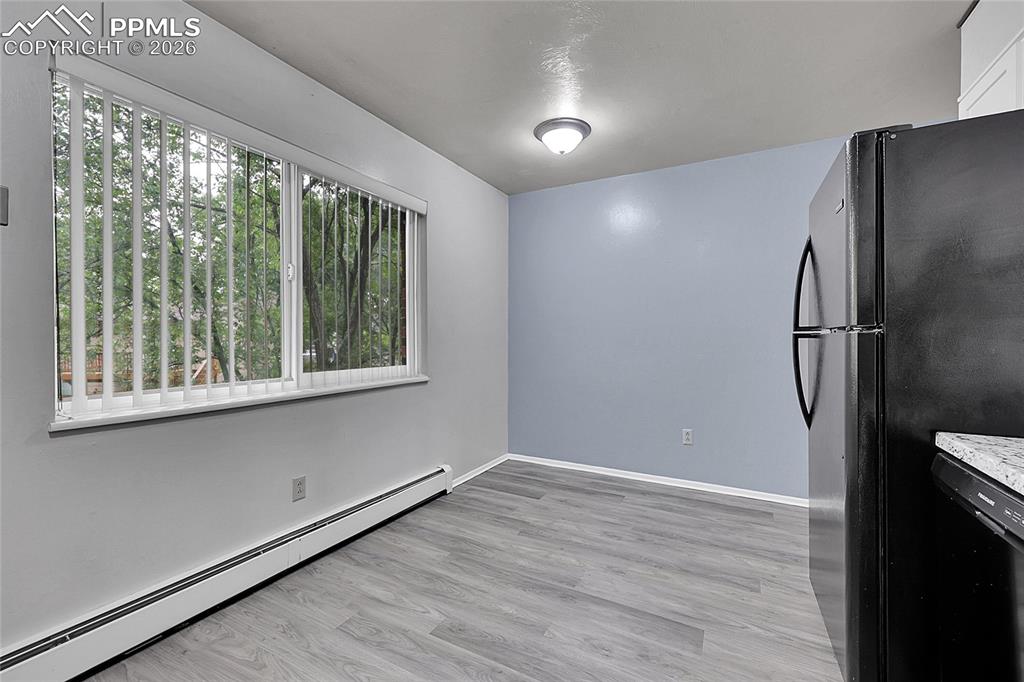 Unfurnished dining area with baseboard heating and light wood-style flooring