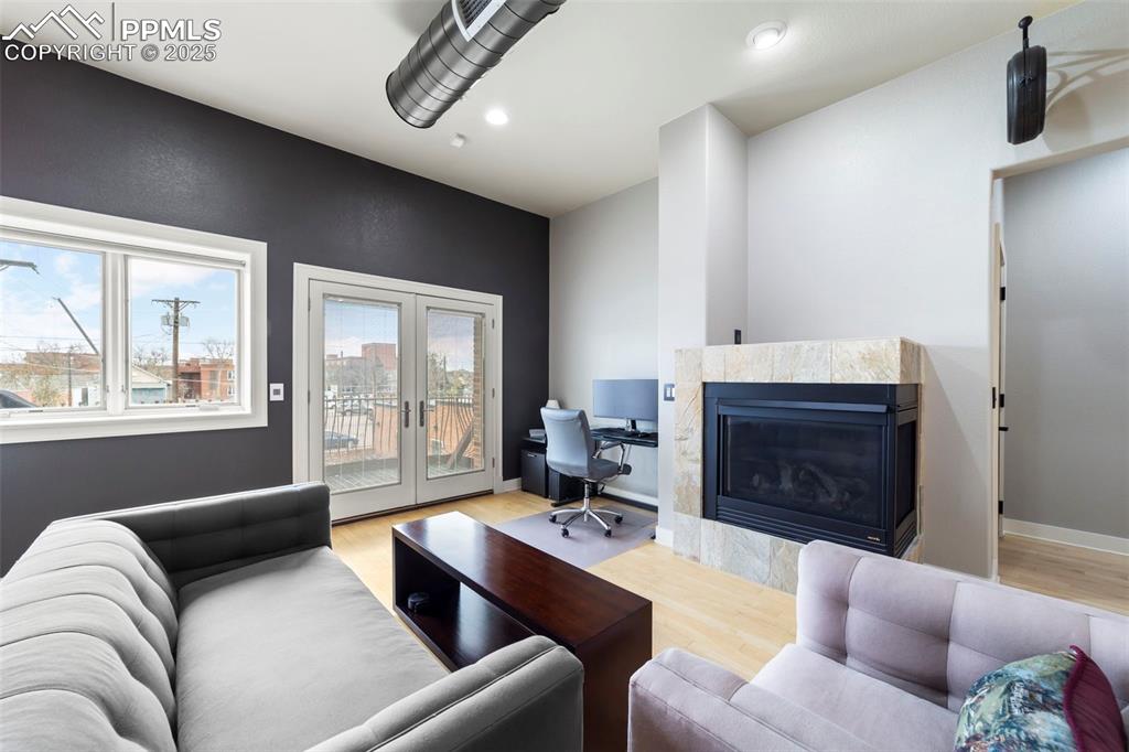 Living room featuring a tiled fireplace, french doors, hardwood floors, an office area, and recessed lighting