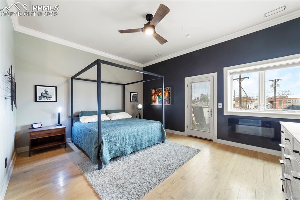 Primary Bedroom with crown molding, hardwood floors, ceiling fan, and access to exterior balcony/patio.