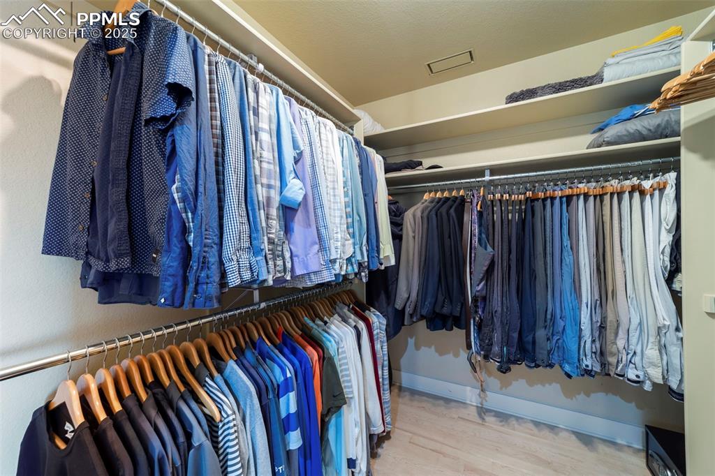 Primary bedroom walk in closet featuring light wood-style floors