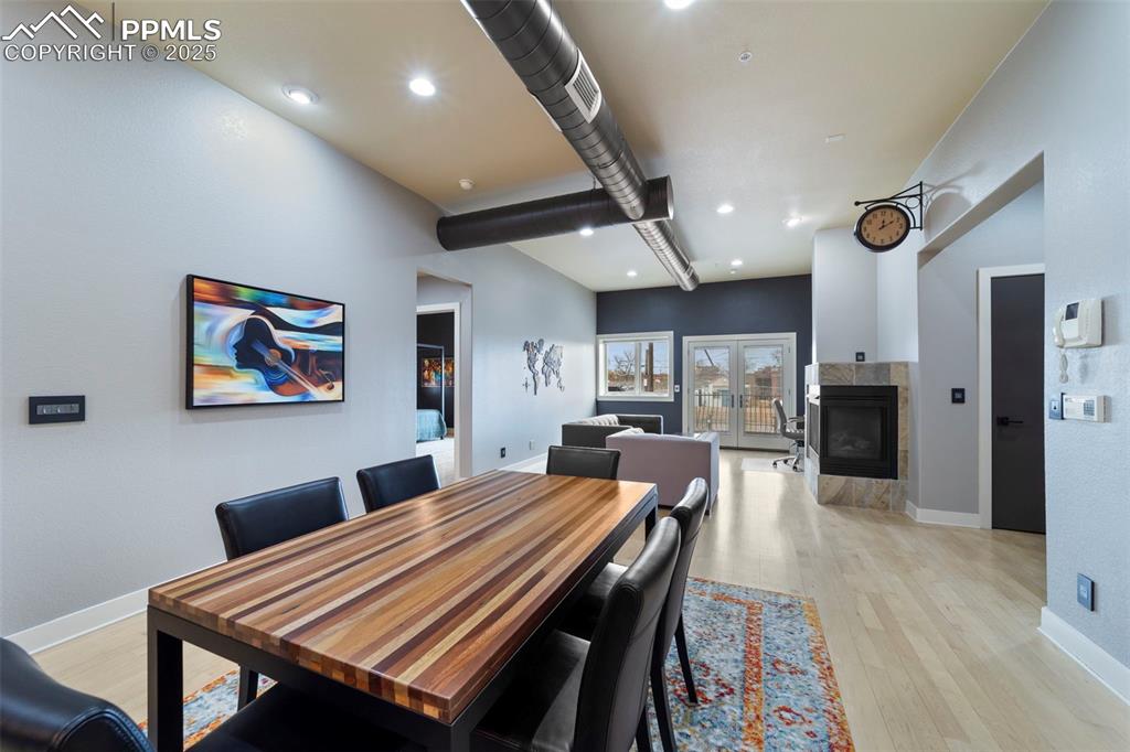 Dining area with hardwood flooring, recessed lighting, a tile fireplace, and beamed ceiling