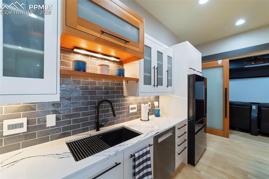 Kitchen featuring white cabinets, decorative backsplash, glass insert cabinets, quartz countertops, and open shelves