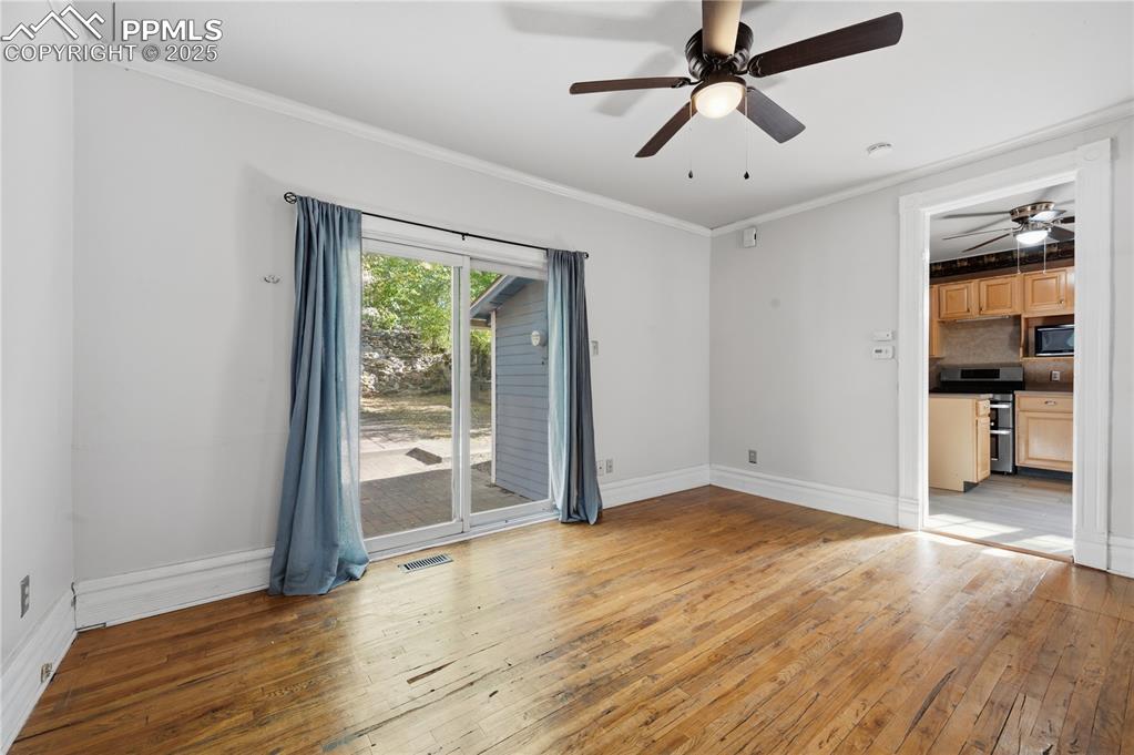 Spare room with light wood-style floors, ornamental molding, and a ceiling fan