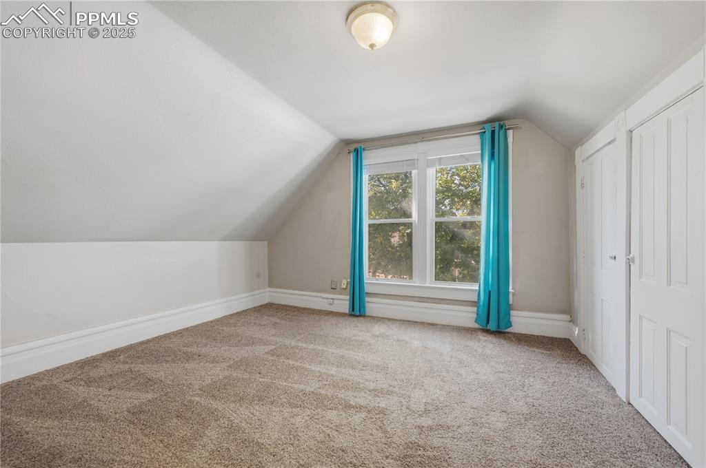 Additional living space featuring vaulted ceiling and carpet