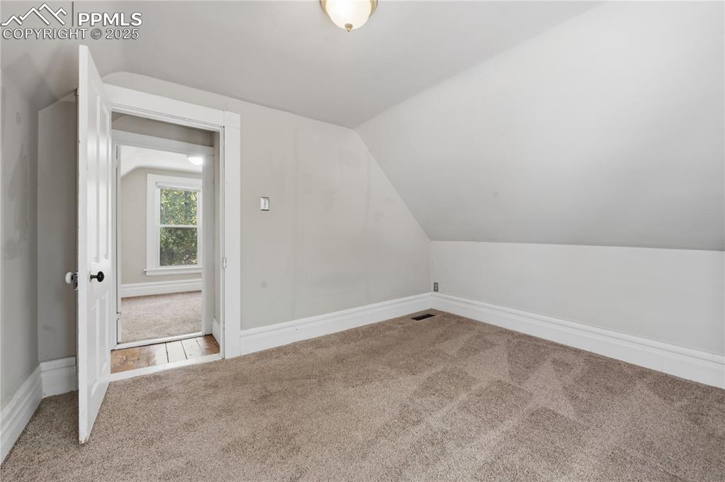 Additional living space with carpet floors and lofted ceiling