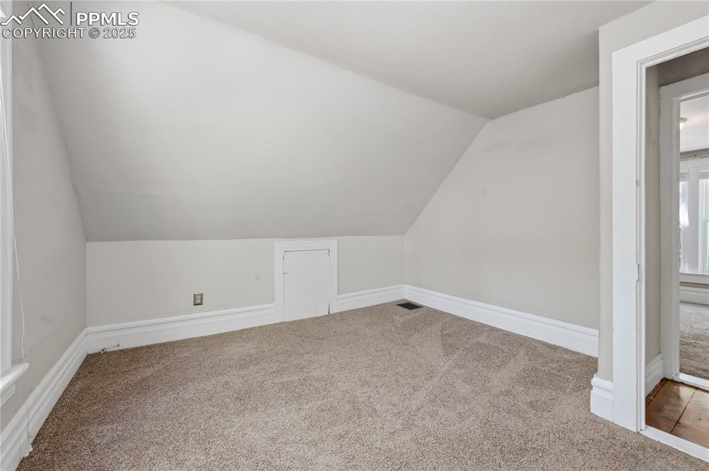 Additional living space with carpet flooring and vaulted ceiling