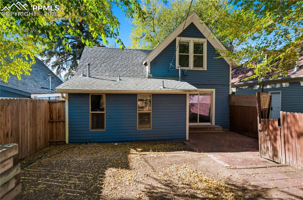 Back of house with roof with shingles and a fenced backyard