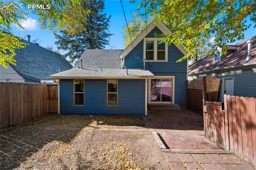 Back of property featuring a fenced backyard and a shingled roof