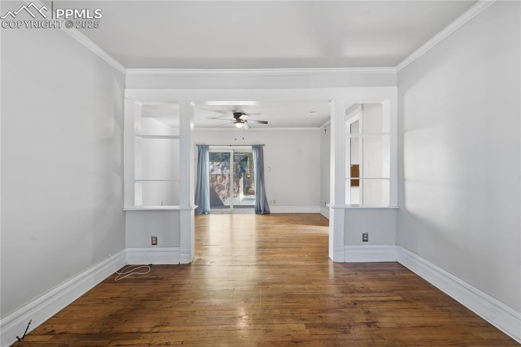 Unfurnished room with dark wood finished floors, crown molding, and ceiling fan