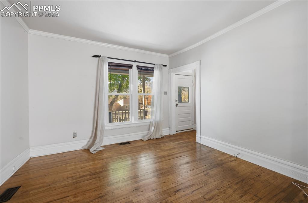 Spare room with ornamental molding and wood-type flooring