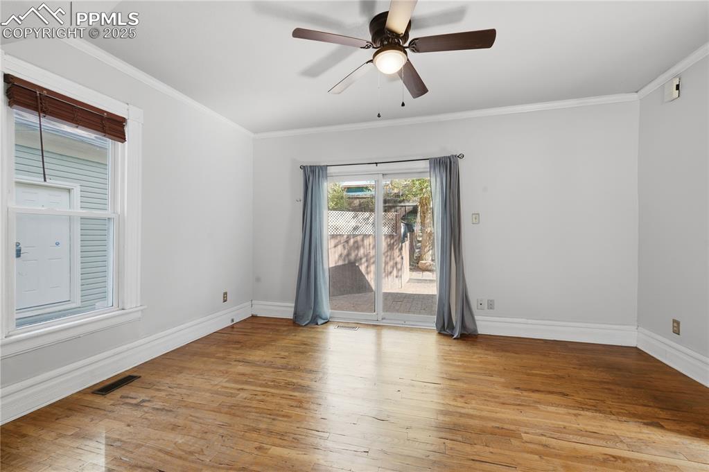 Spare room with light wood finished floors, ornamental molding, and a ceiling fan