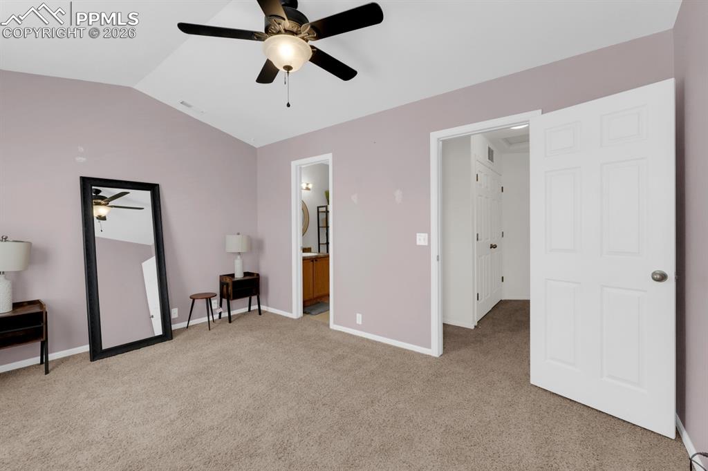 Primary bedroom with light colored carpet, connected bathroom, and a ceiling fan
