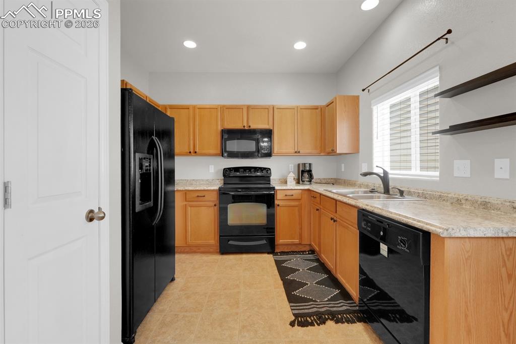 Kitchen with black appliances, open shelves, light countertops, recessed lighting, and light wood finish cabinets