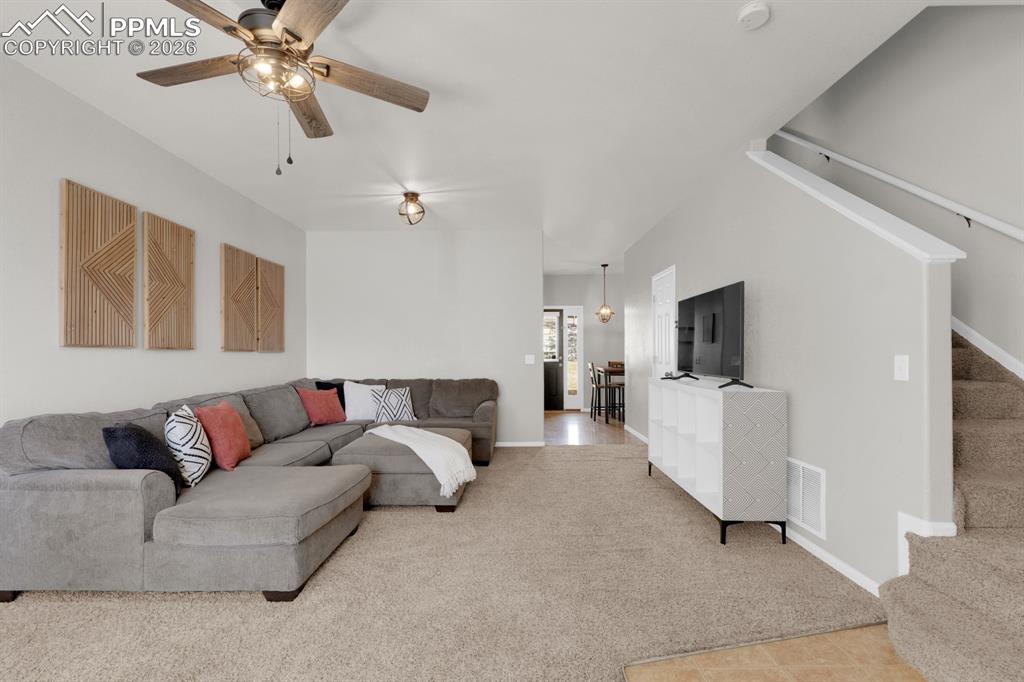 Living area with light colored carpet and ceiling fan