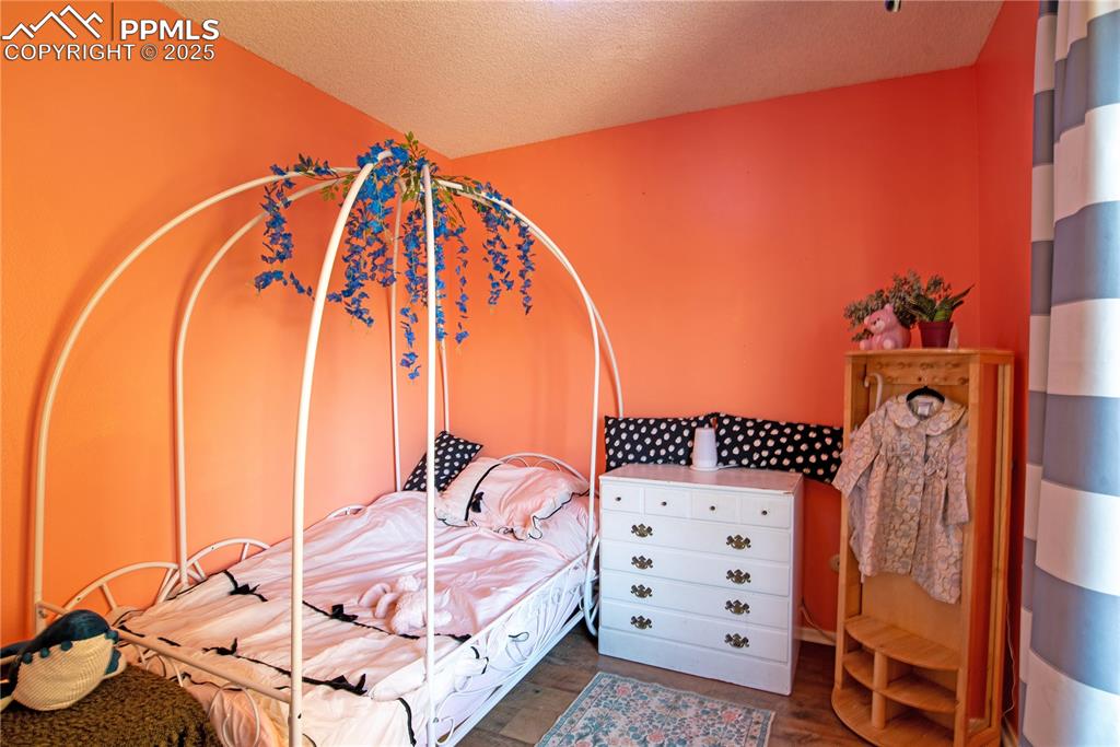 Bedroom with a textured ceiling and wood finished floors