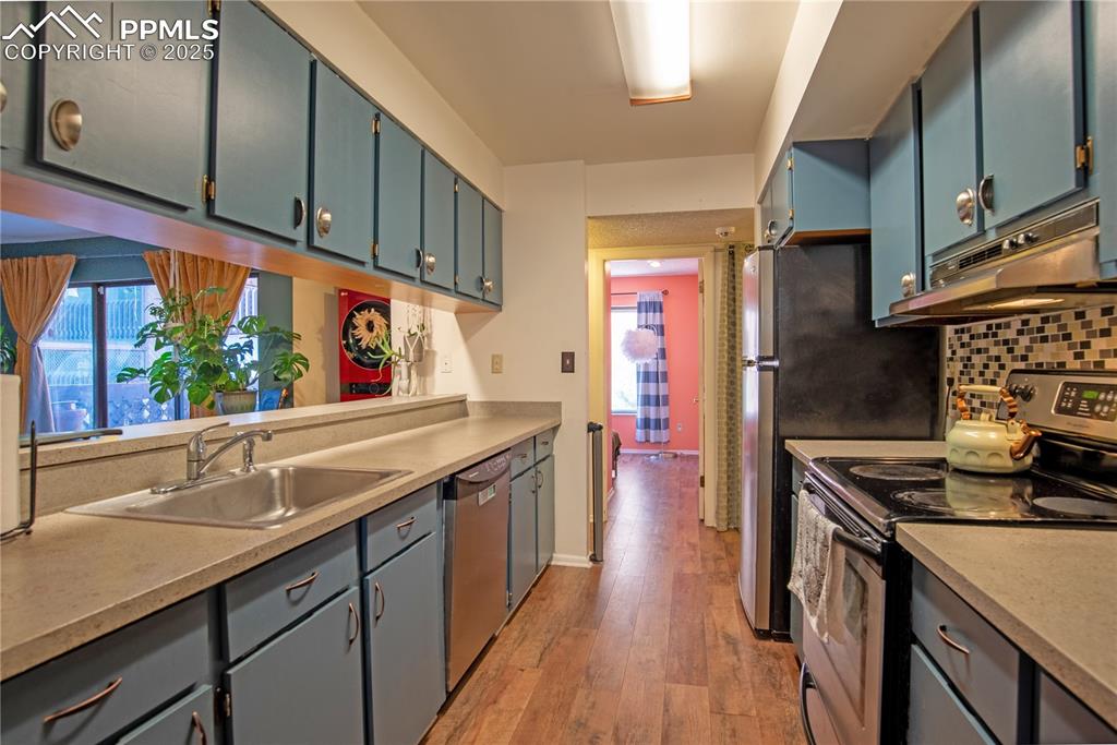Kitchen with stainless steel appliances, light countertops, under cabinet range hood