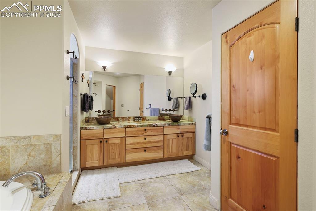Bathroom featuring double vanity, a garden tub, and light tile patterned floors