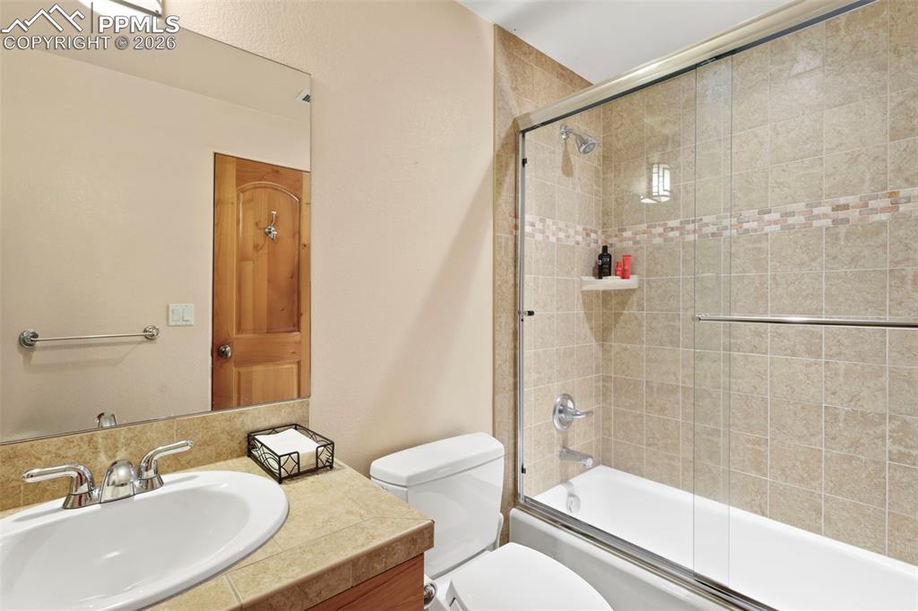 Bathroom with vanity and bath / shower combo with glass door