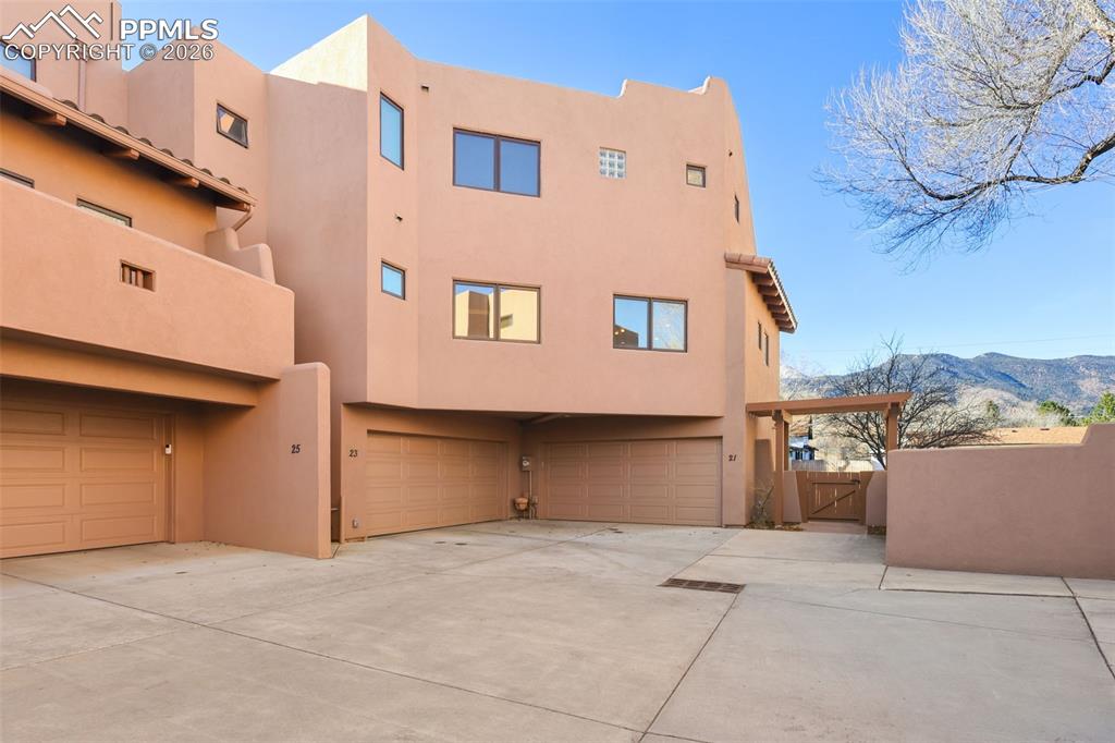 Back of property featuring a mountain view, a garage, stucco siding, a gate, and driveway