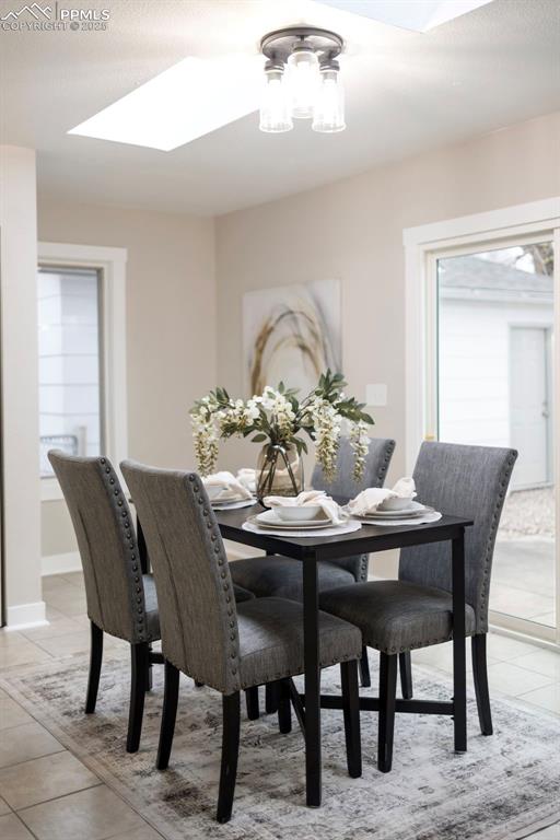 Dining room with light tile patterned floors, a skylight, and a textured ceiling