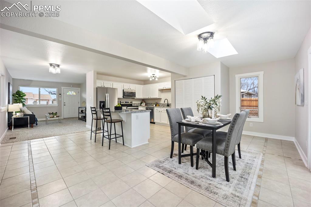 Dining area featuring a skylight and light tile patterned flooring